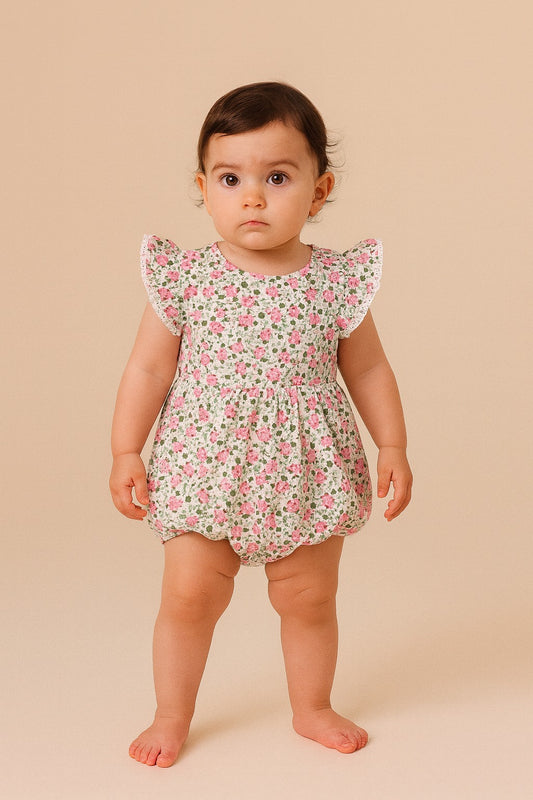 Baby wearing a floral romper against a beige background
