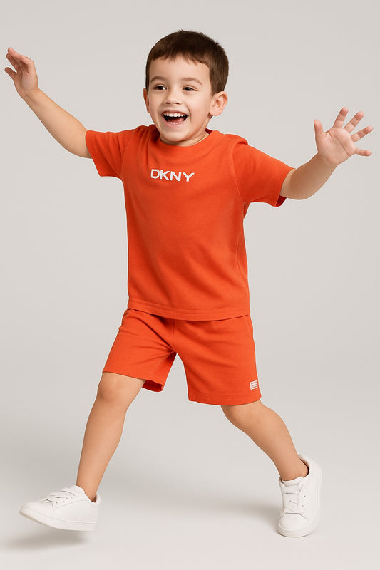 Child wearing an orange DKNY outfit with arms outstretched on a light gray background