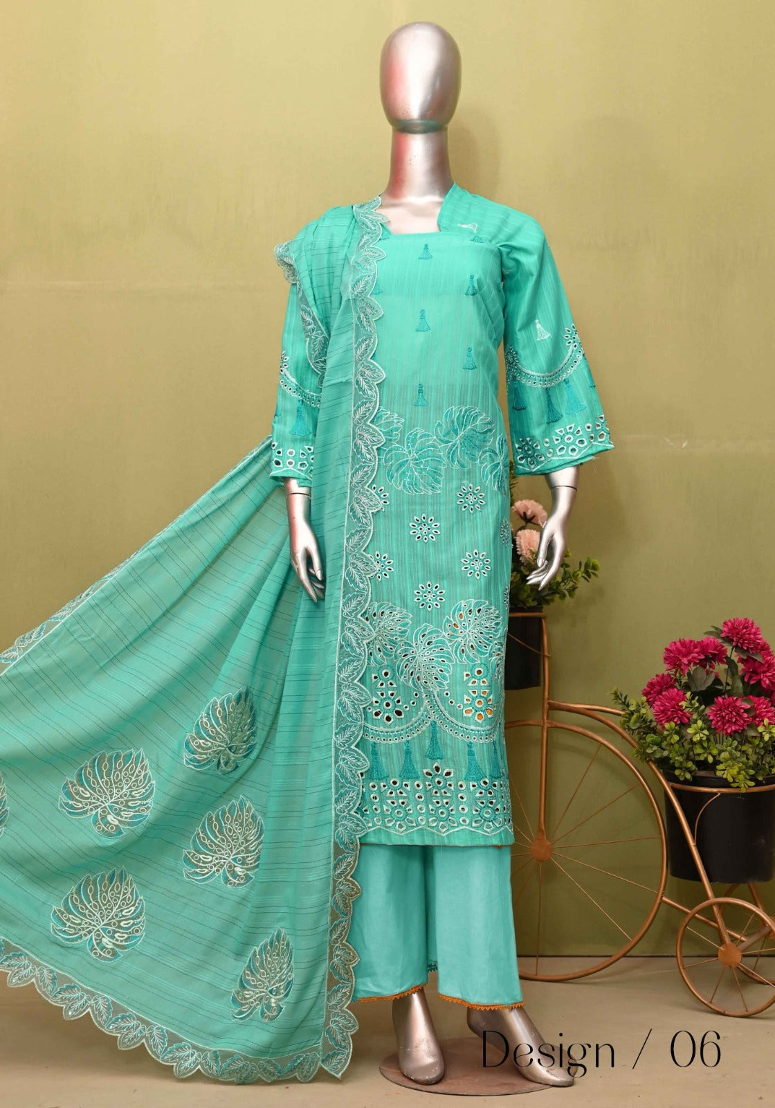 A mannequin displaying a three-piece heavy embroidered lawn outfit in green with floral patterns and a dupatta.