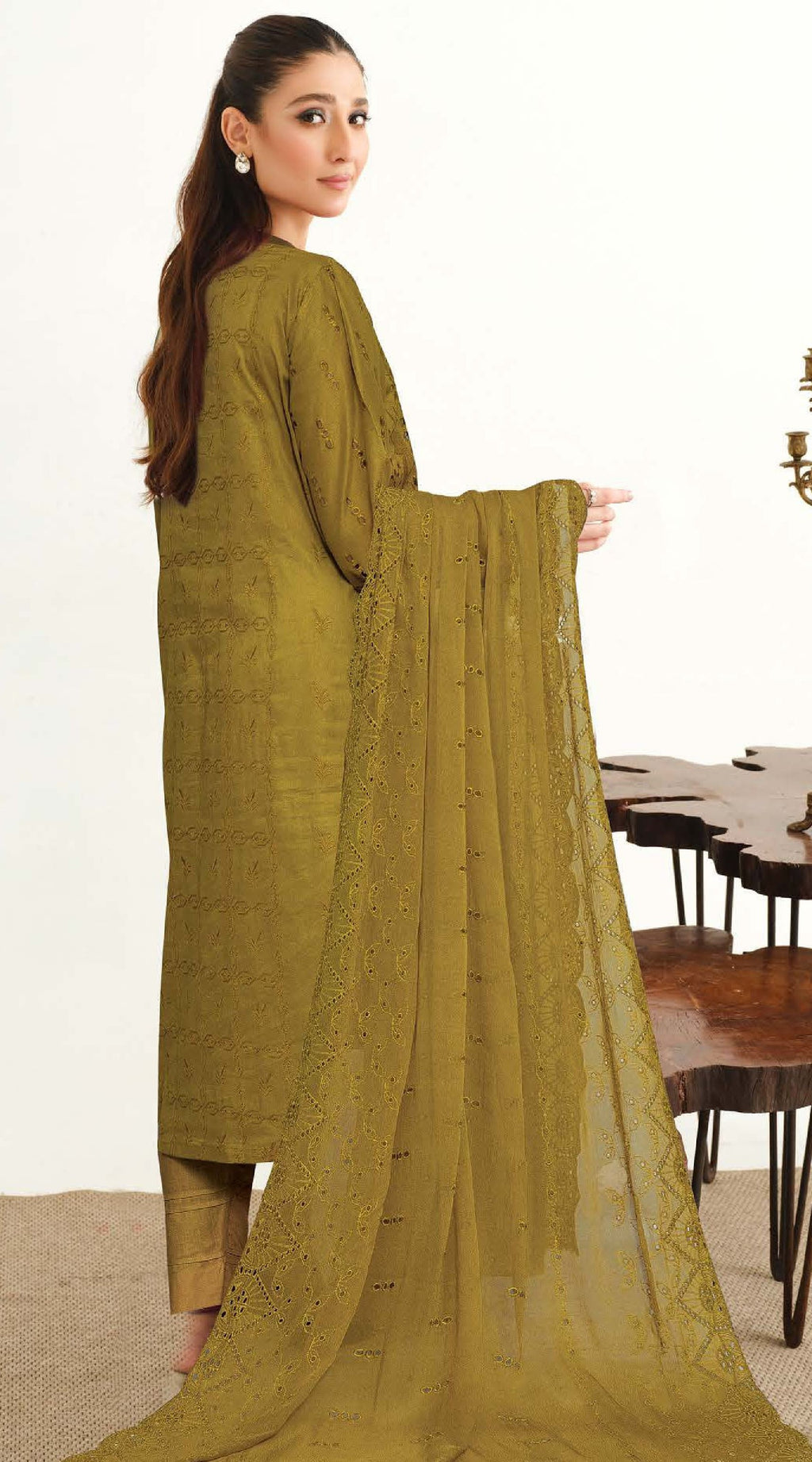 A woman modeling a green 3-piece suit with Chikankari embroidery, consisting of a shirt, pants, and a chiffon dupatta.