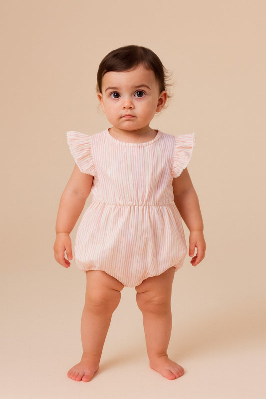 Baby wearing a pink ruffled romper on a beige background