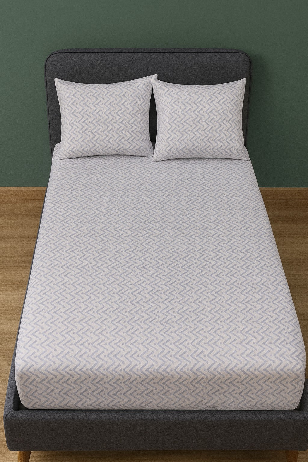 Bed with gray bedsheet  and pillows against a green wall