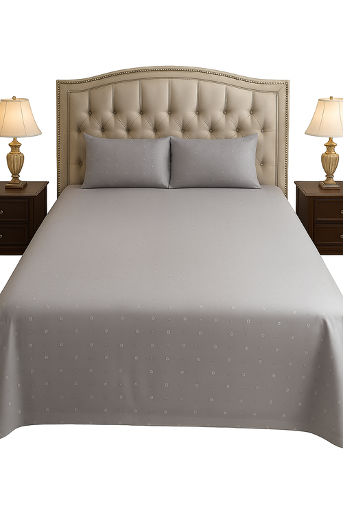 Gray polka dot bedspread on a bed with matching pillows and nightstands with lamps.