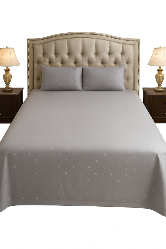 Gray polka dot bedspread on a bed with matching pillows and nightstands with lamps.