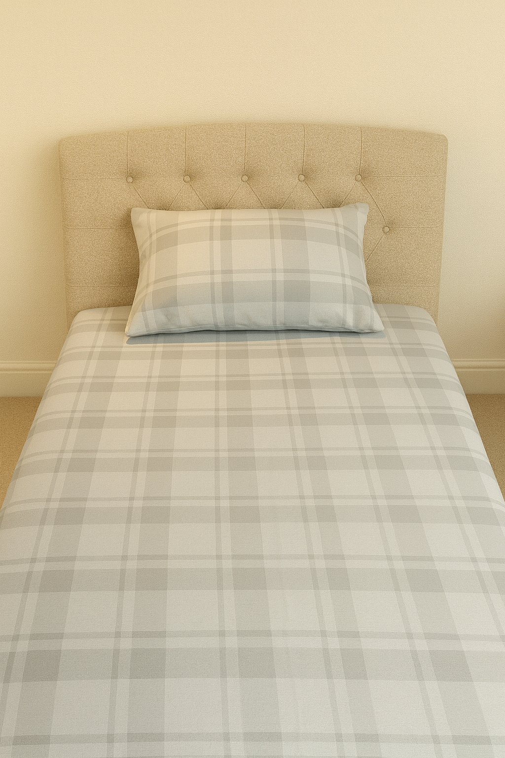 Bedsheet with plaid bedding and pillow against a beige headboard.