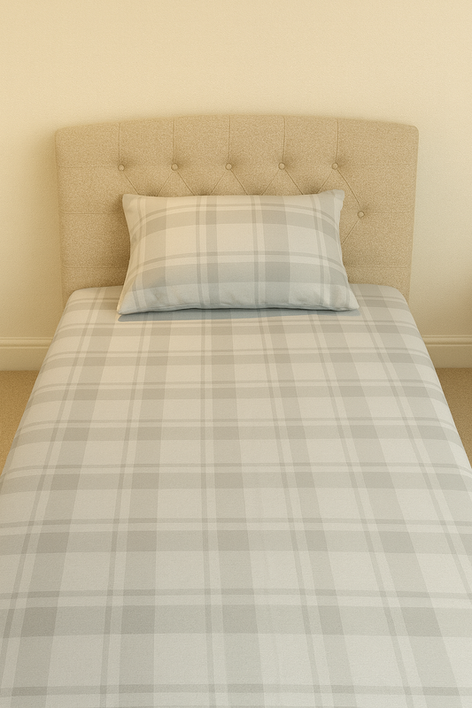 Bedsheet with plaid bedding and pillow against a beige headboard.