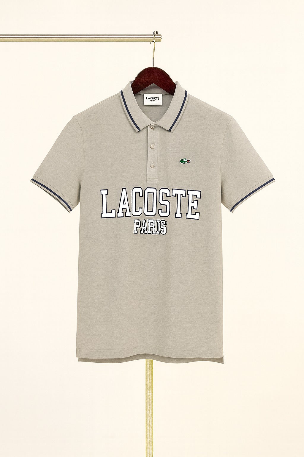 Beige Lacoste polo shirt on a hanger against a white background