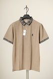 Beige polo shirt with black collar and trim on a hanger against a beige background