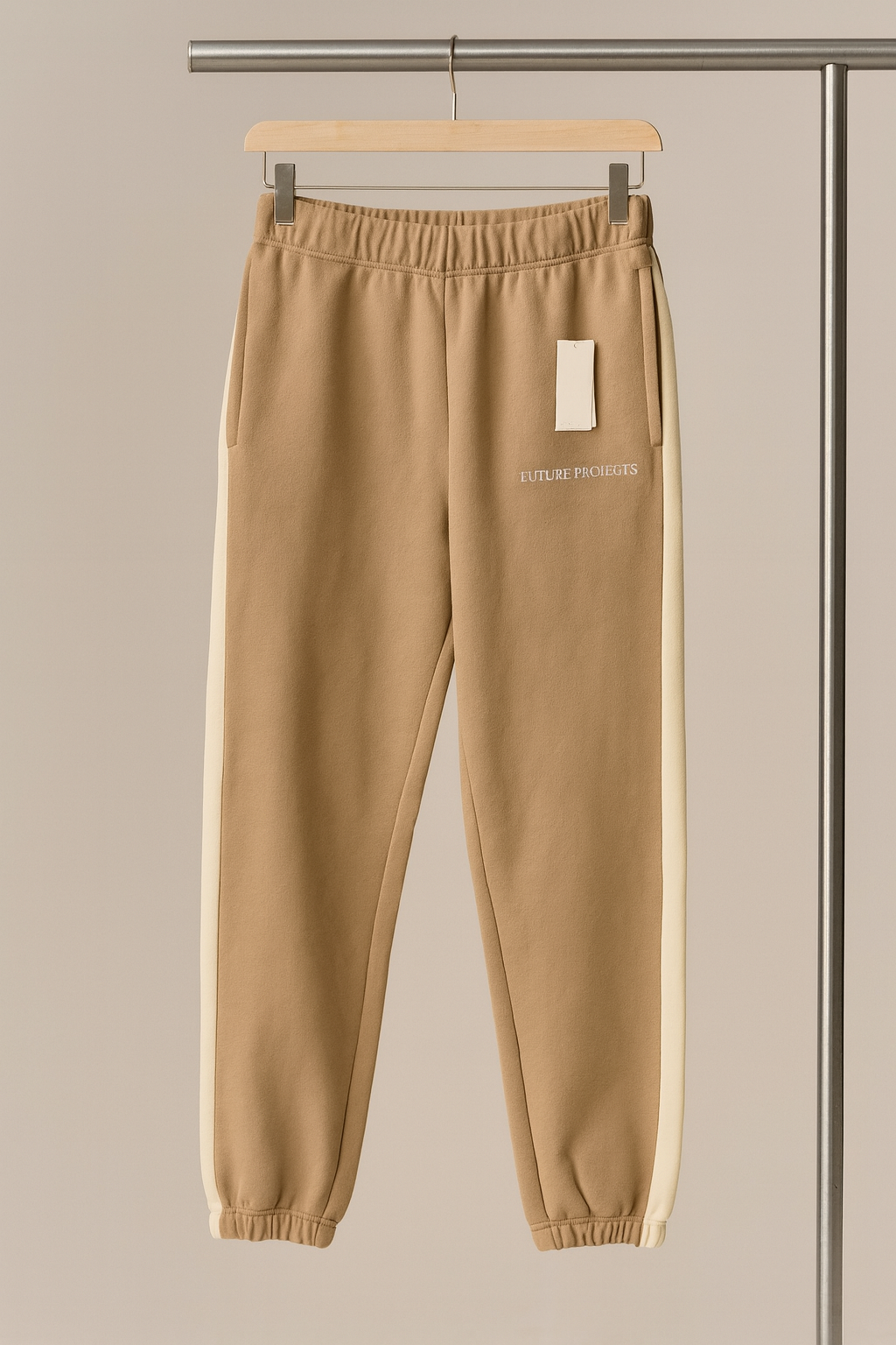 Beige sweatpants on a hanger against a neutral background