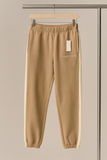 Beige sweatpants on a hanger against a neutral background