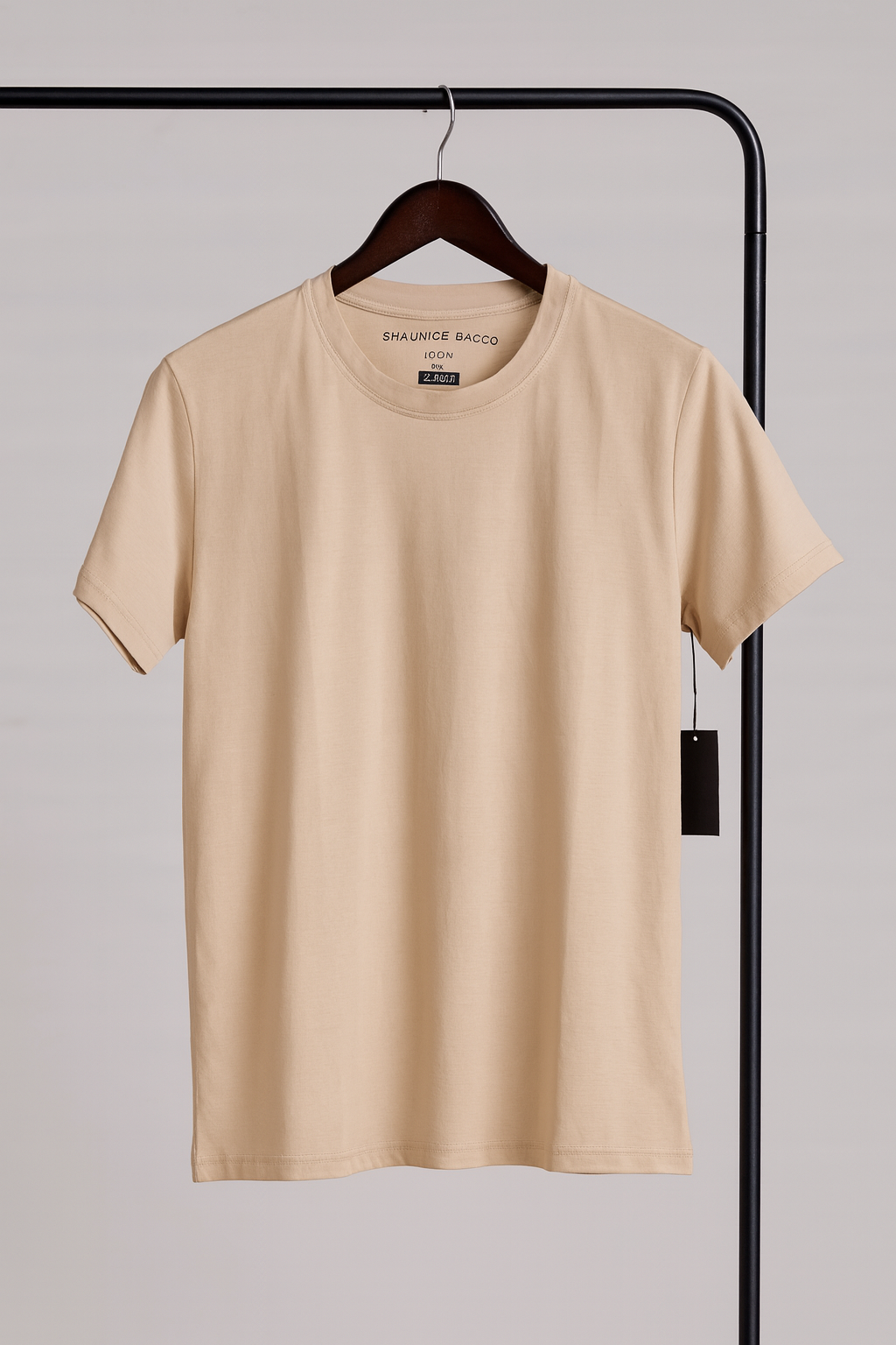 Beige t-shirt on a hanger with a plain background