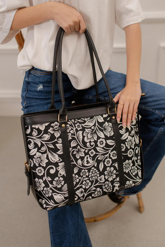Person holding a black handbag with white floral pattern