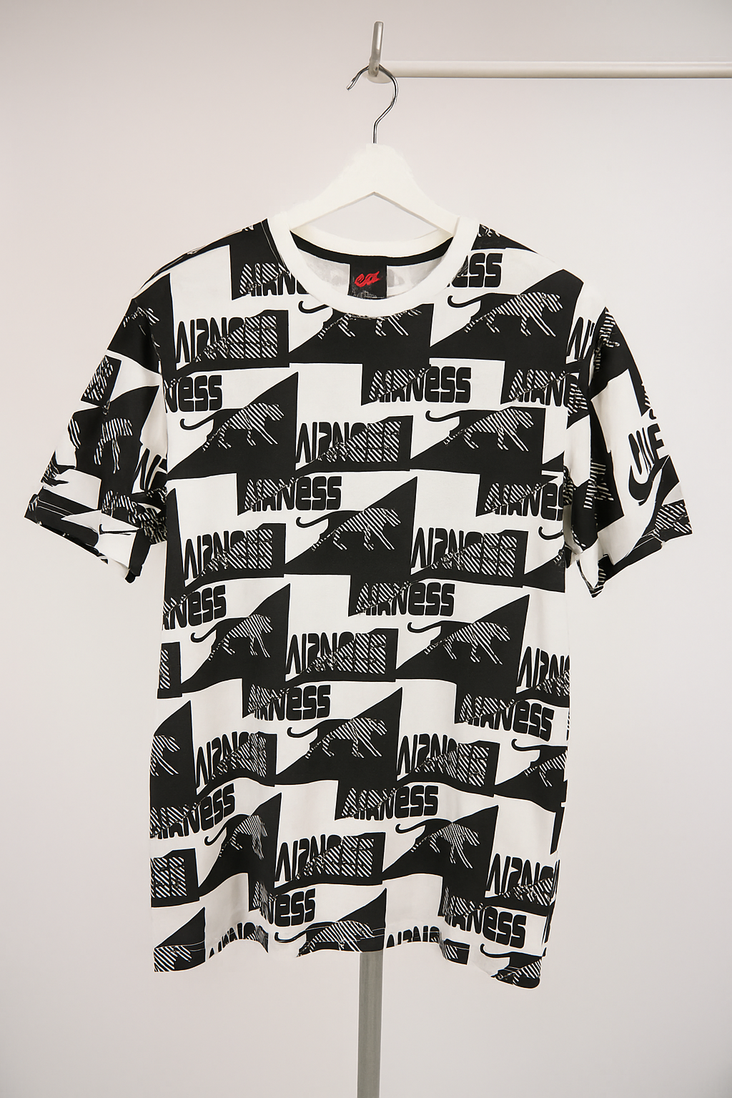 Black and white t-shirt with brand logos on a hanger against a white background