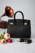 Black handbag with flowers and a vintage record player on a light gray background