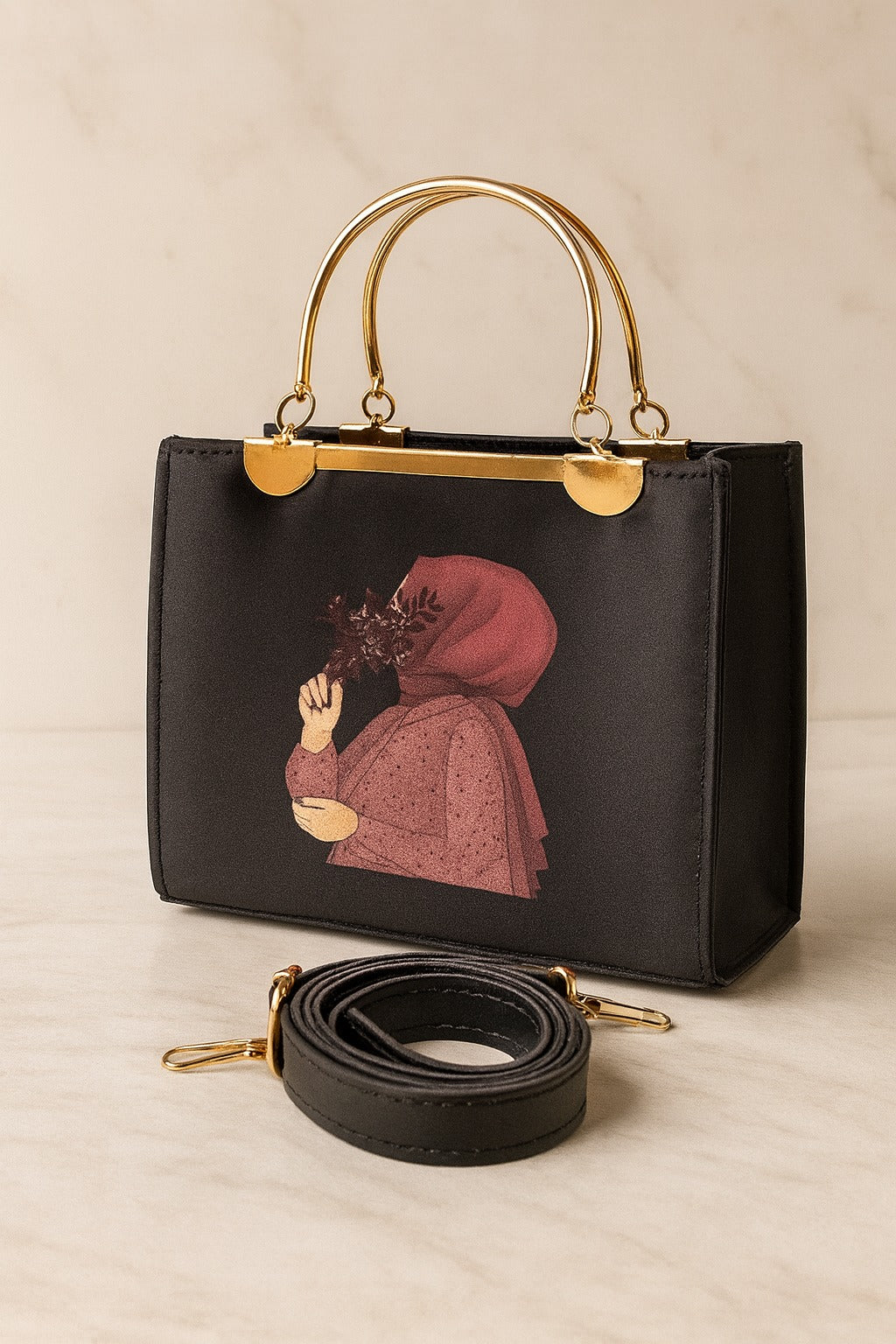 Black handbag with gold handle and detachable strap on a beige background