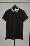 Black polo shirt with plaid collar on a hanger against a gray background