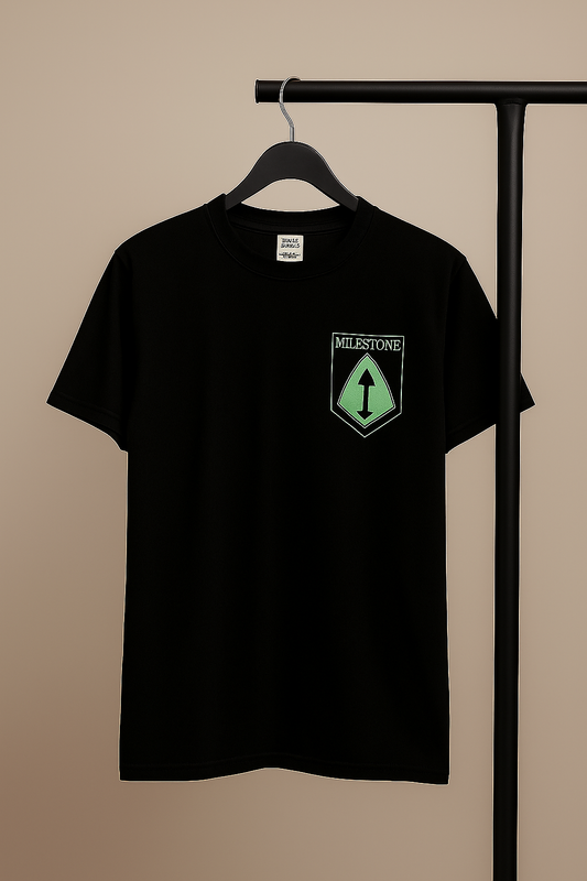 Black t-shirt with a green and white logo on a hanger against a beige background