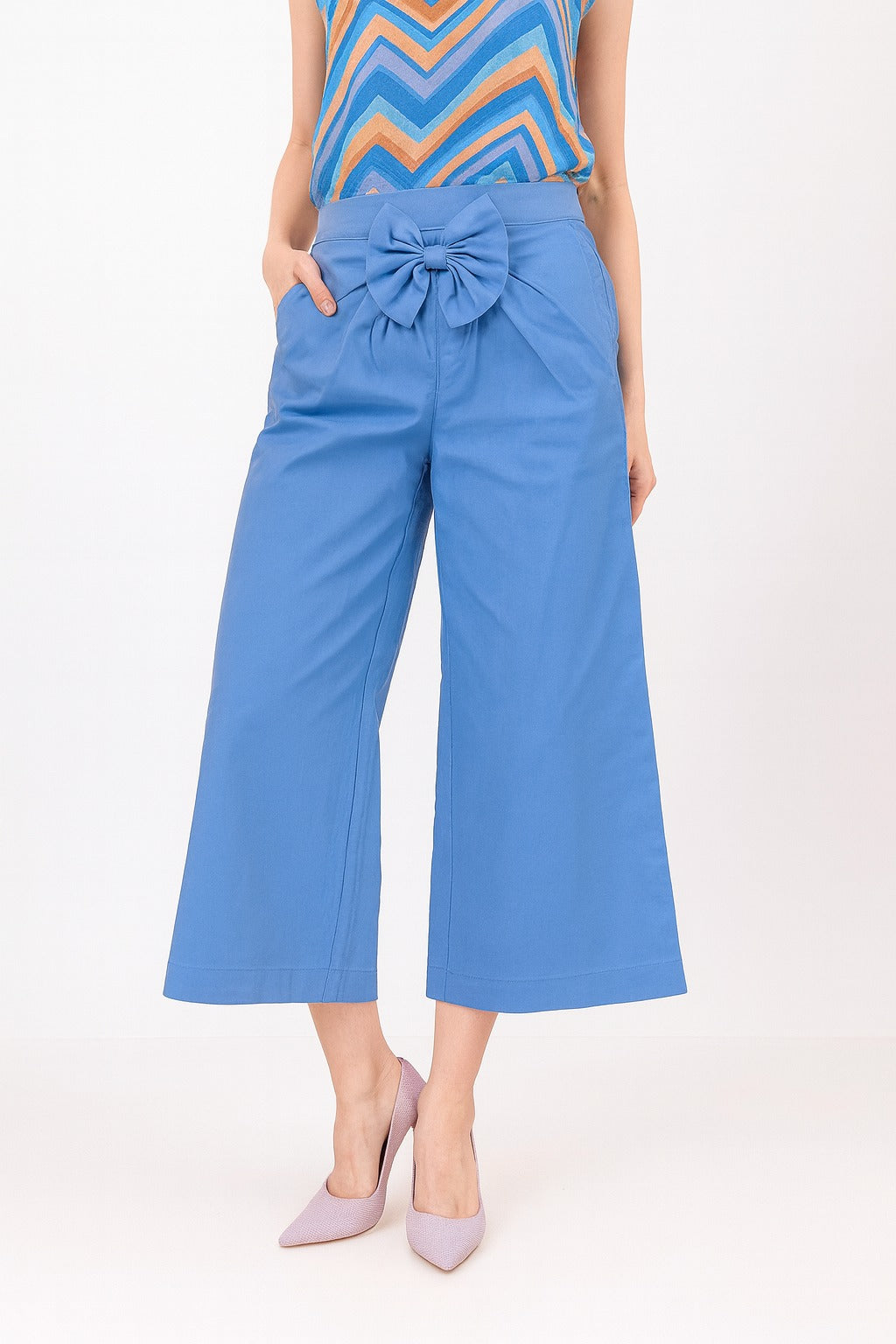 Blue pants with a bow detail worn by a person on a white background
