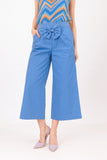 Blue pants with a bow detail worn by a person on a white background