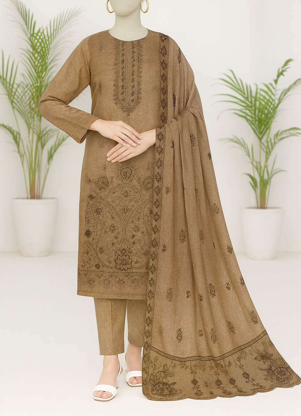 Brown embroidered outfit with dupatta on a mannequin against a white background with plants.