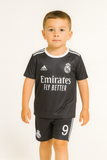 Child wearing a black sports outfit with visible branding on a white background