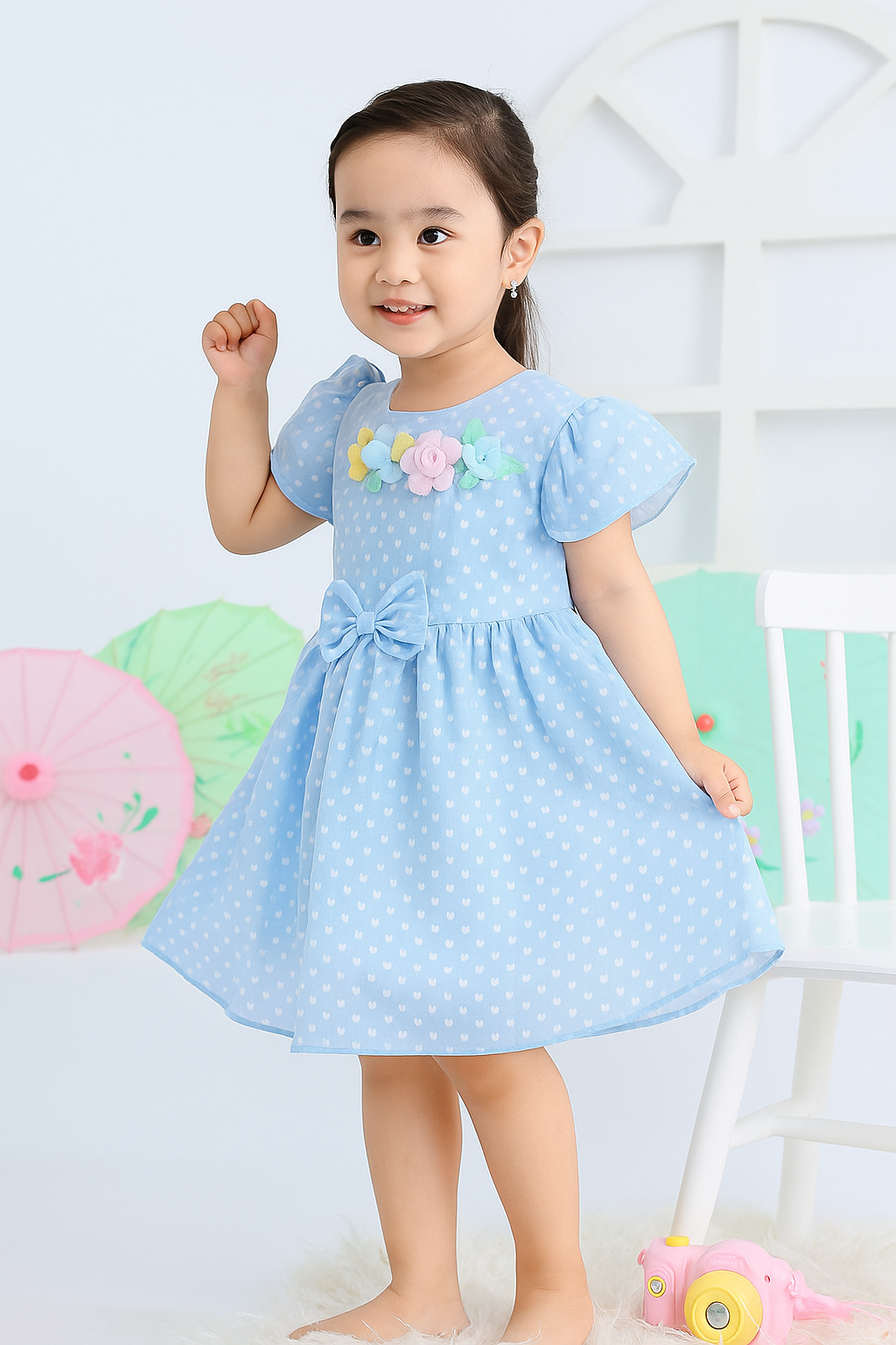 Child wearing a light blue dress with floral embroidery against a white background