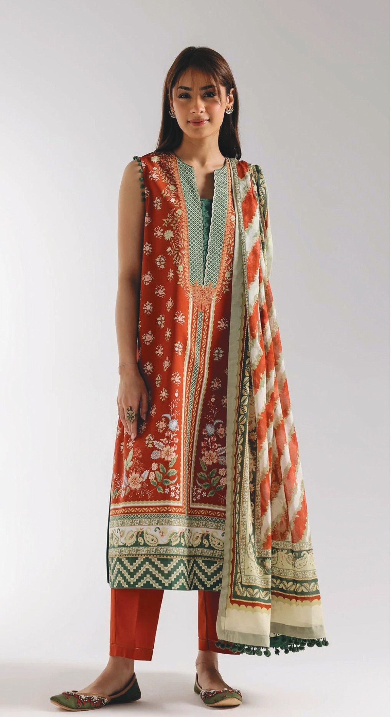 Woman wearing a traditional outfit with a red and green printed dress and matching dupatta on a white background