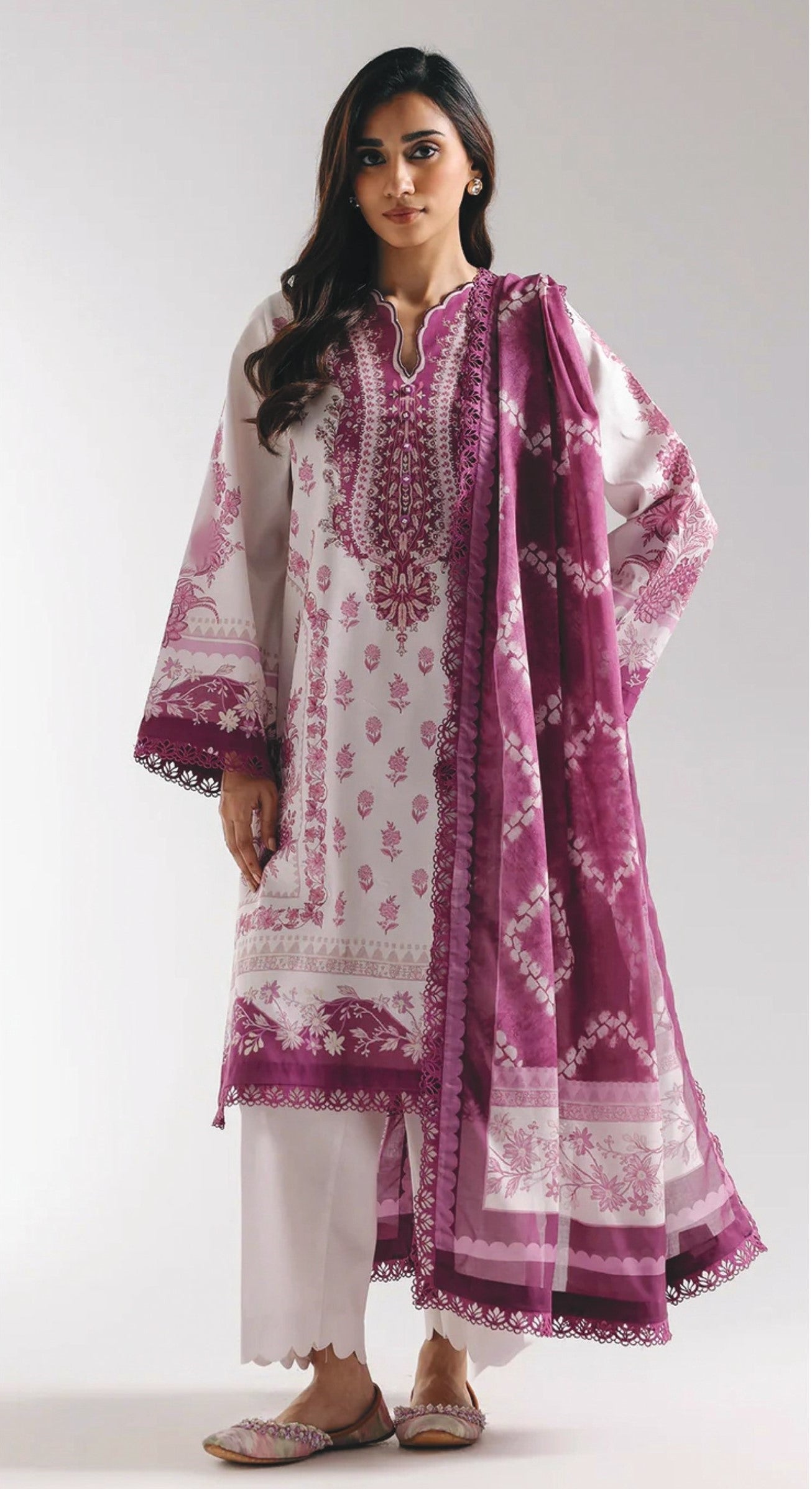 Woman wearing a white kurta with pink trouser and matching dupatta on a white background