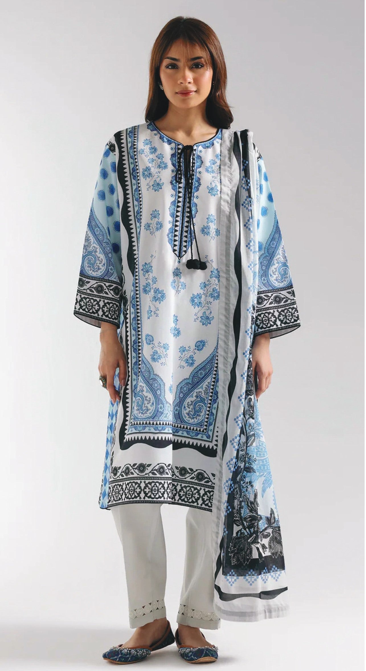 Woman wearing a blue and white patterned kurta with white pants on a white background