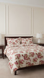 Floral bedding set on a bed in a bedroom with a lamp and nightstands.