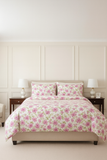 Floral bedding set on a bed in a bedroom with matching pillows.