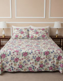 Floral patterned bedspread on a bed with matching pillows, set against a beige wall.