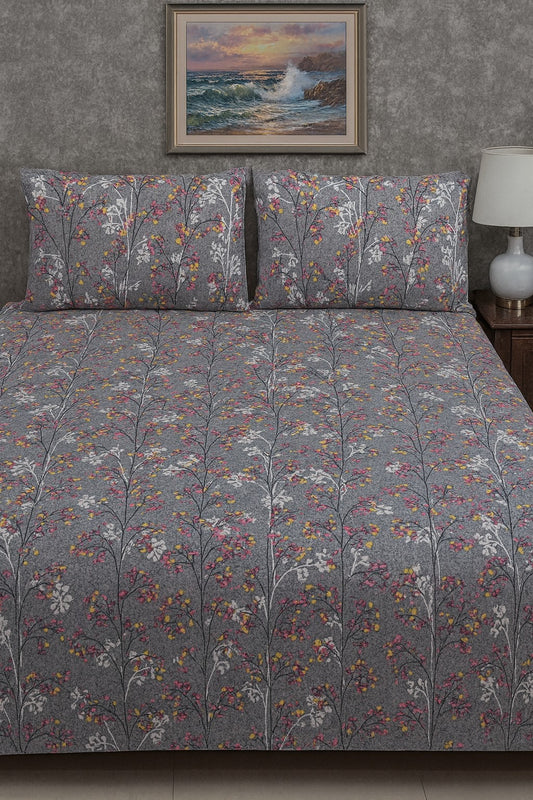 Floral patterned bedspread on a bed with matching pillows, framed artwork above, and a lamp on a nightstand.