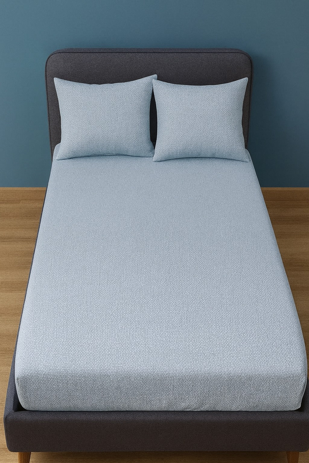 Gray Bedsheet with matching pillows on a bed against a blue wall.