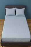 Gray Bedsheet with matching pillows on a bed against a blue wall.