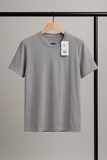 Gray t-shirt on a hanger with a tag against a neutral background