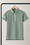 Green polo shirt with text and numbers on a hanger against a light gray background