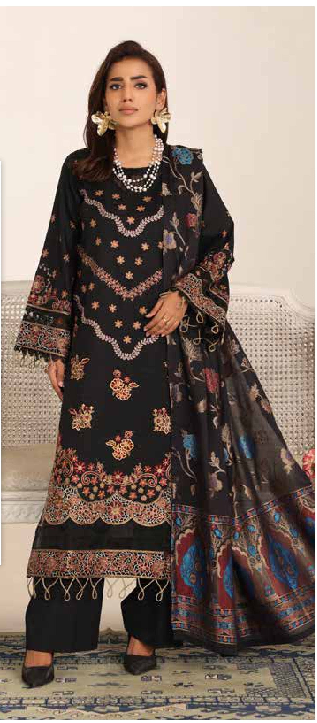 Woman wearing a black embroidered traditional outfit with a colorful dupatta.