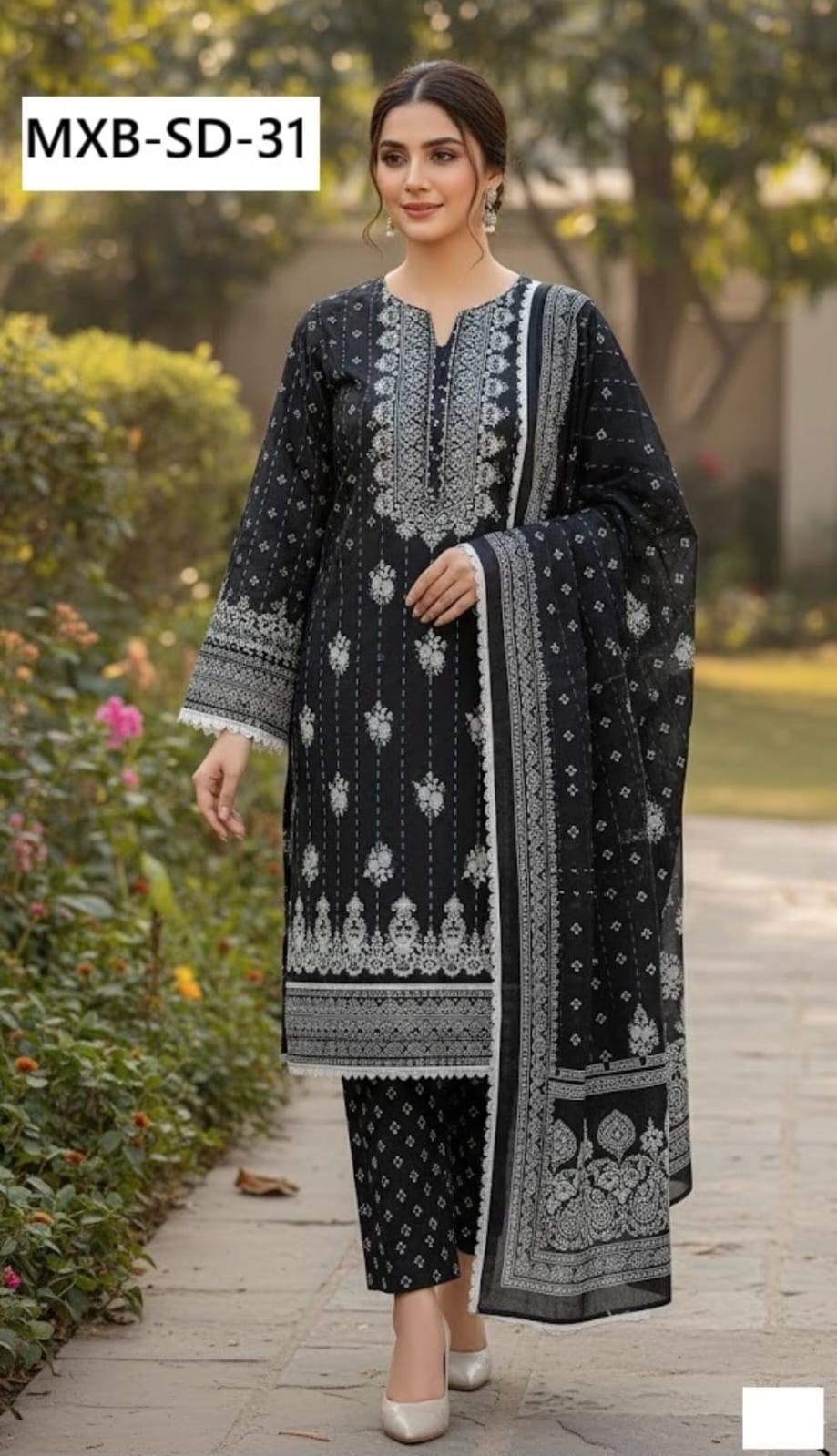 Woman wearing a black and white embroidered outfit with 'MXB-SD-31' label in a garden setting.