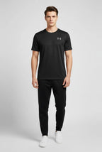 Man wearing a black Under Armour t-shirt and pants on a light gray background