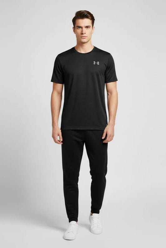 Man wearing a black Under Armour t-shirt and pants on a light gray background