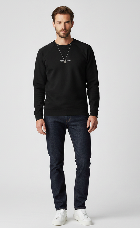 Man wearing a black sweater, dark jeans, and white shoes on a light gray background