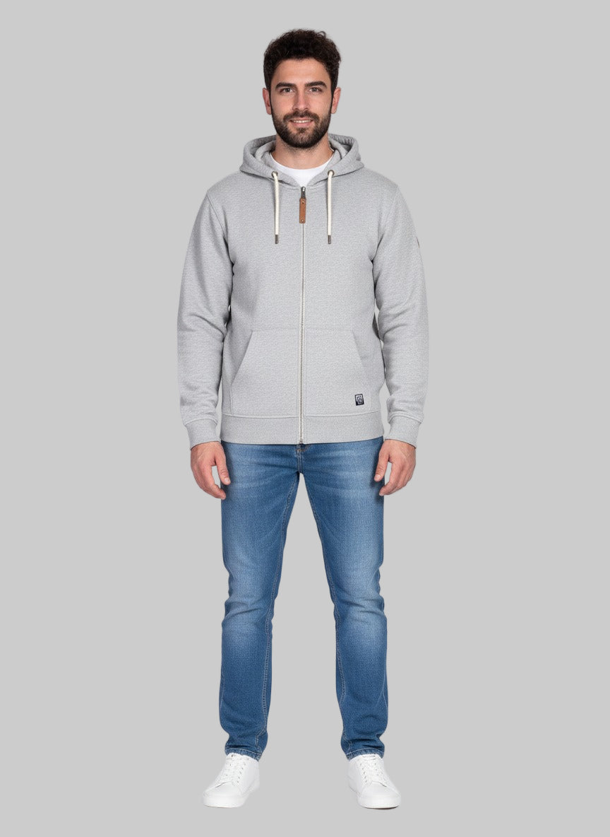 Man wearing a gray hoodie and blue jeans on a gray background