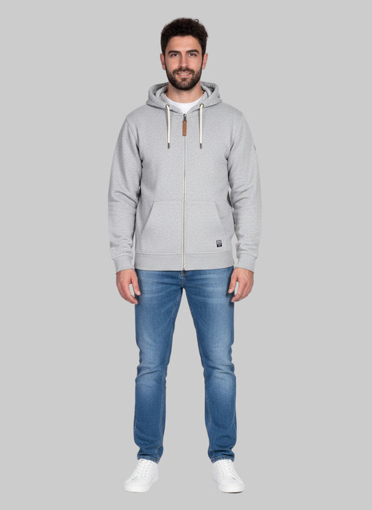 Man wearing a gray hoodie and blue jeans on a gray background