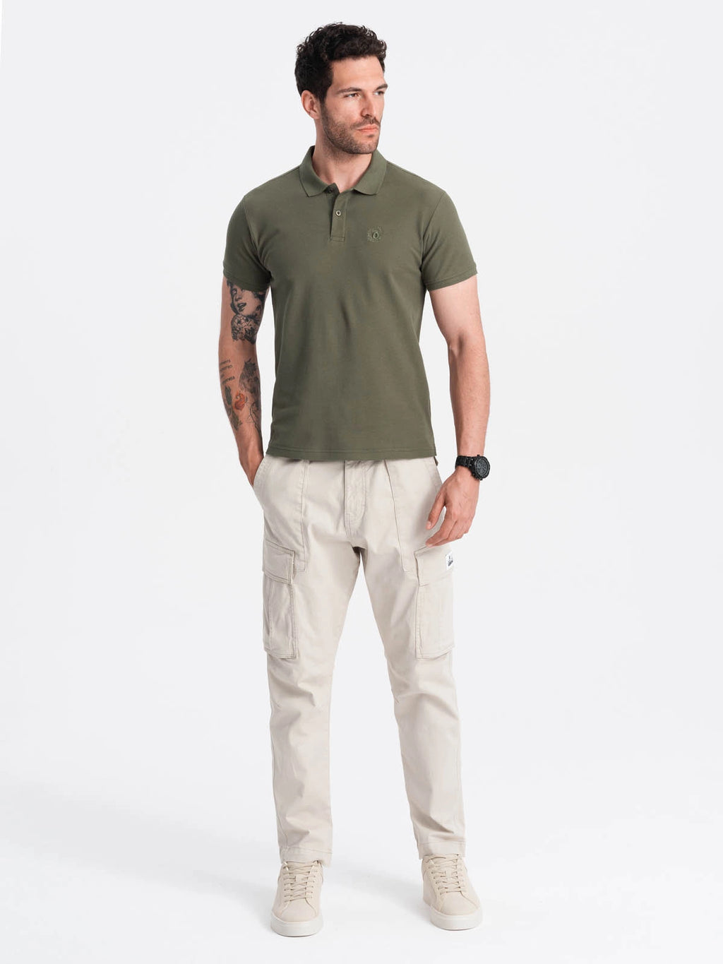 Man wearing a green polo shirt and beige cargo pants on a white background