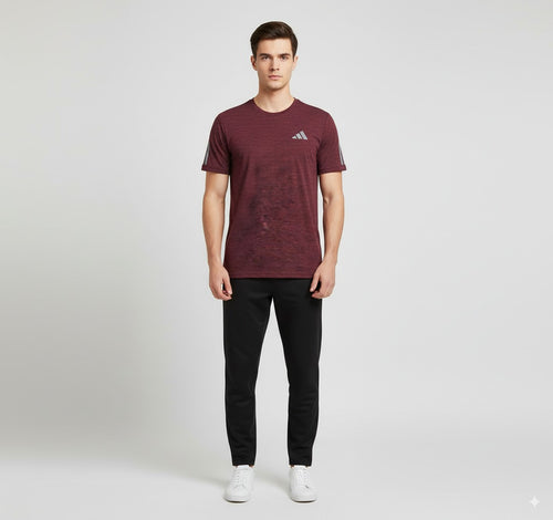 Man wearing a maroon Adidas t-shirt and black pants on a white background