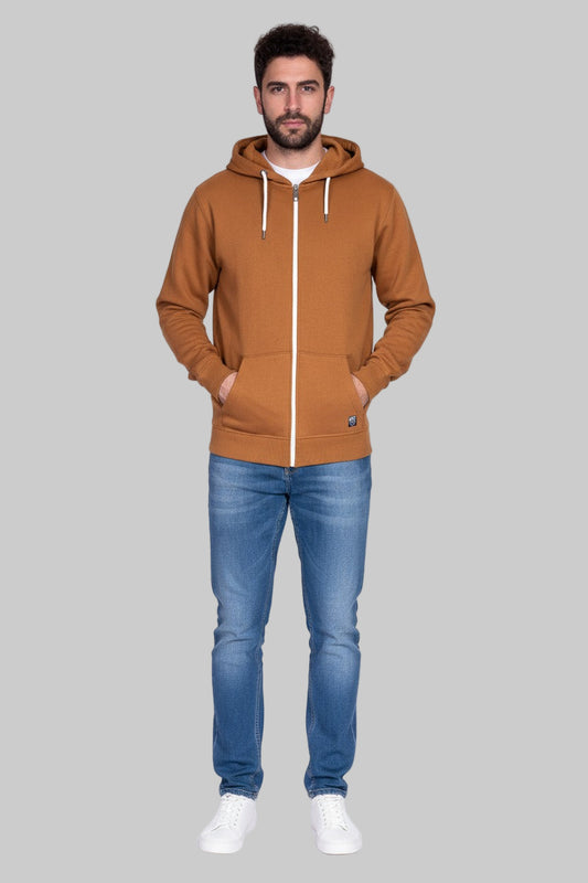 Man wearing a mastard hoodie and blue jeans on a gray background