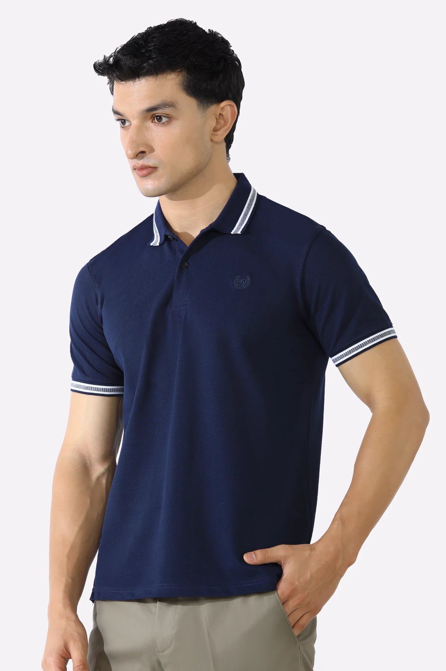 Man wearing a navy blue polo shirt with white trim on a plain background