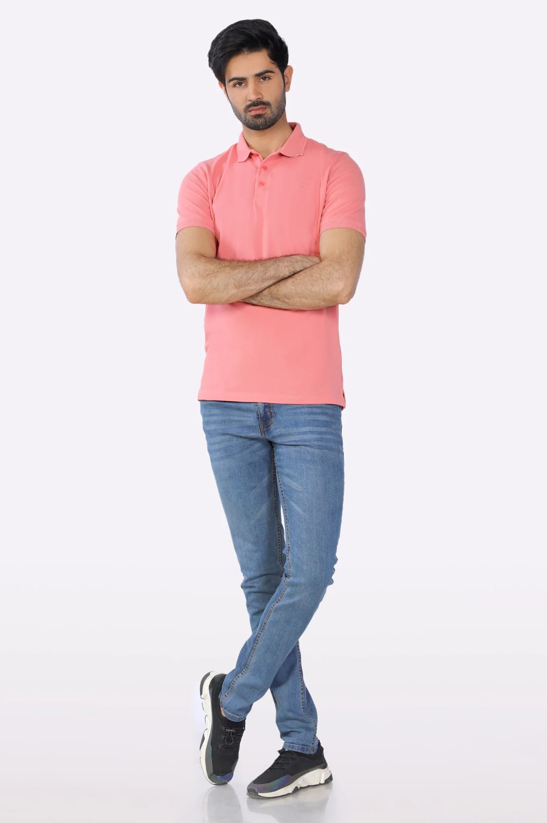 Man wearing a pink polo shirt and blue jeans on a white background