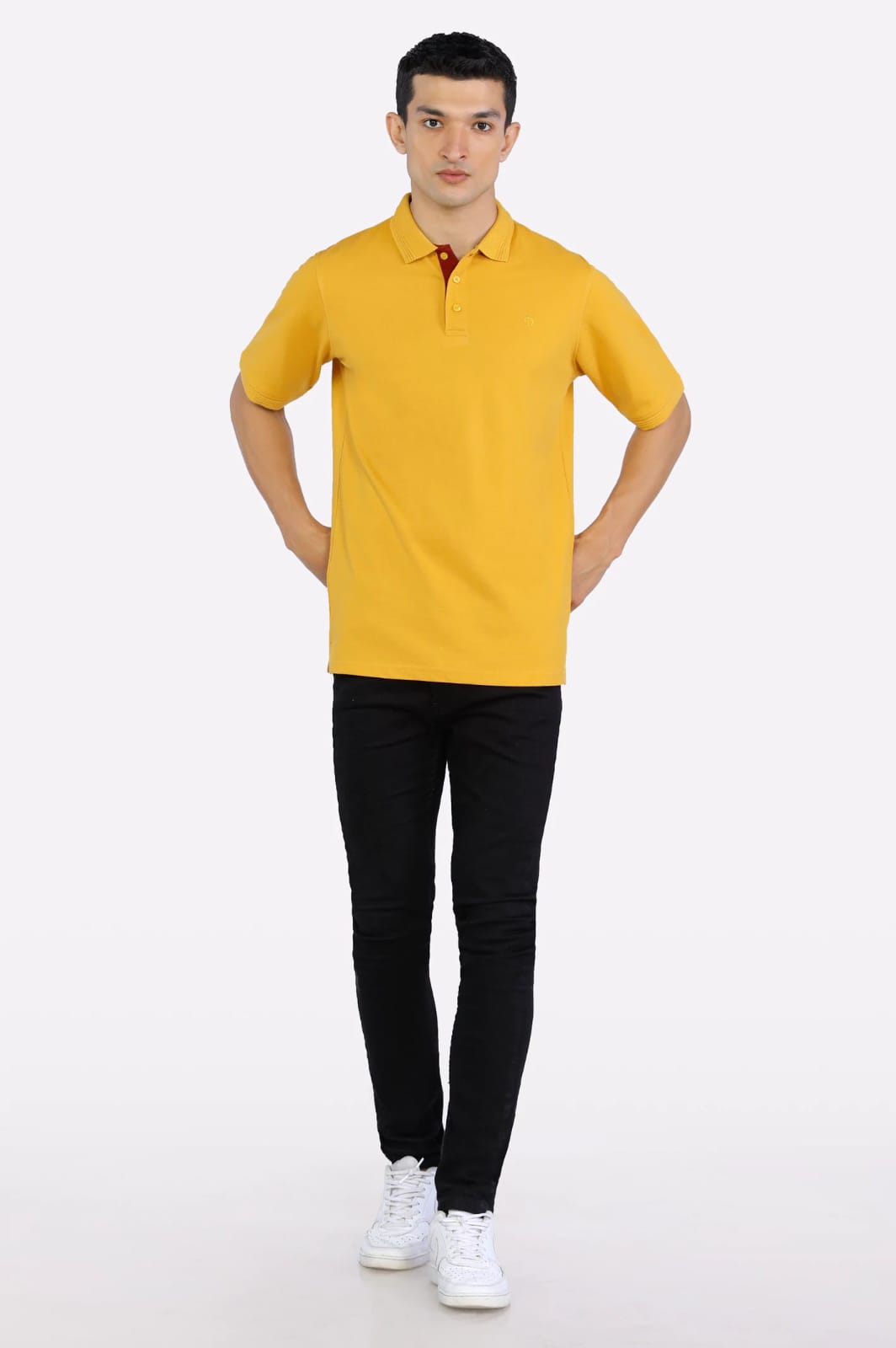 Man wearing a yellow polo shirt and black pants on a white background